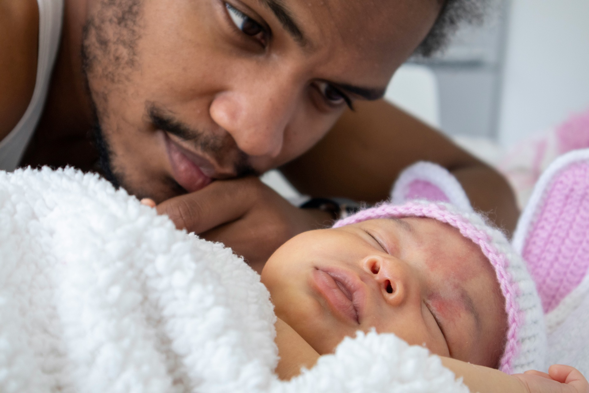 An awake parent looking at their sleeping baby