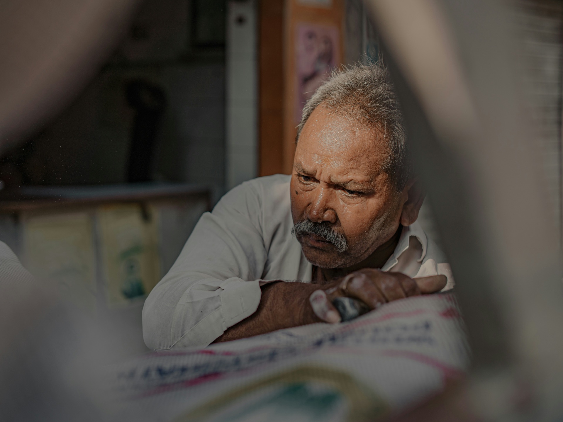 Una persona mayor mirando por una ventana con los brazos apoyados en el borde