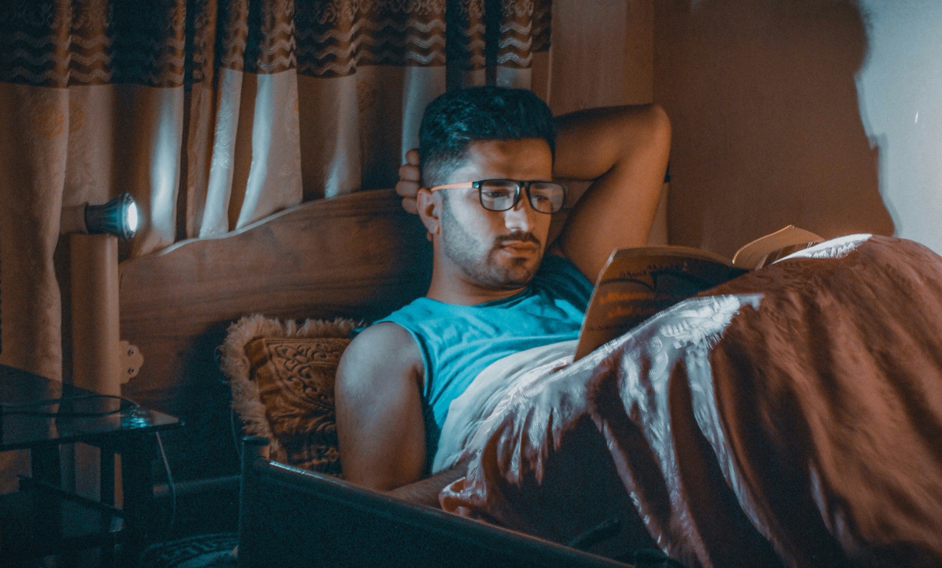 Hombre despierto en la cama de noche leyendo un libro para volver a dormirse